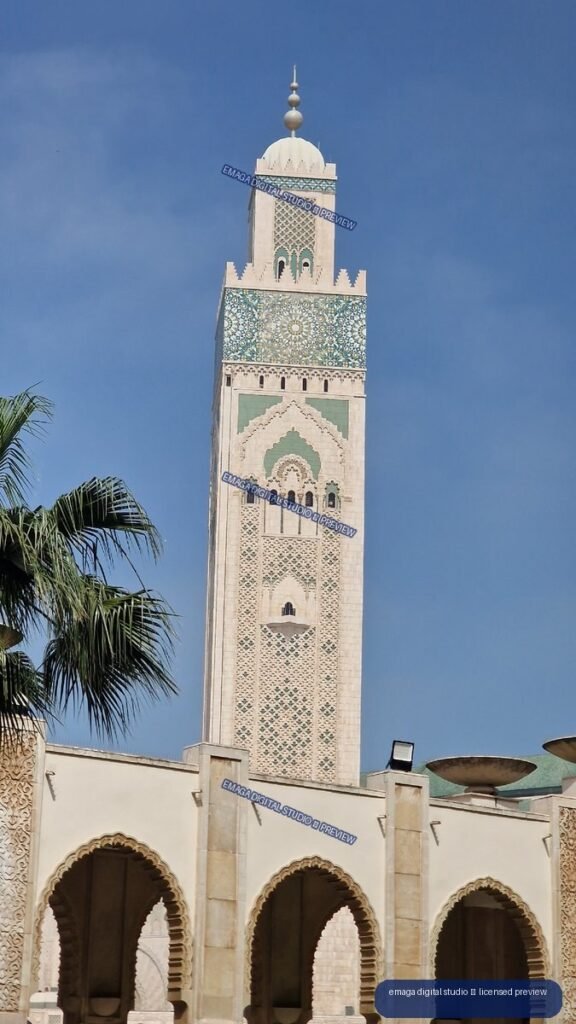 Ornate mosque minaret framed by palm leaves under blue sky — Casablanca, Morocco