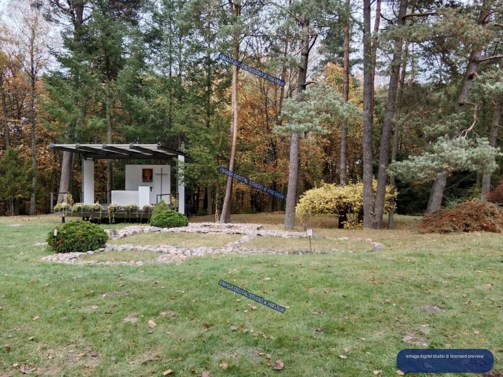 Small white chapel in a landscaped garden surrounded by autumn-colored trees and lawn.
