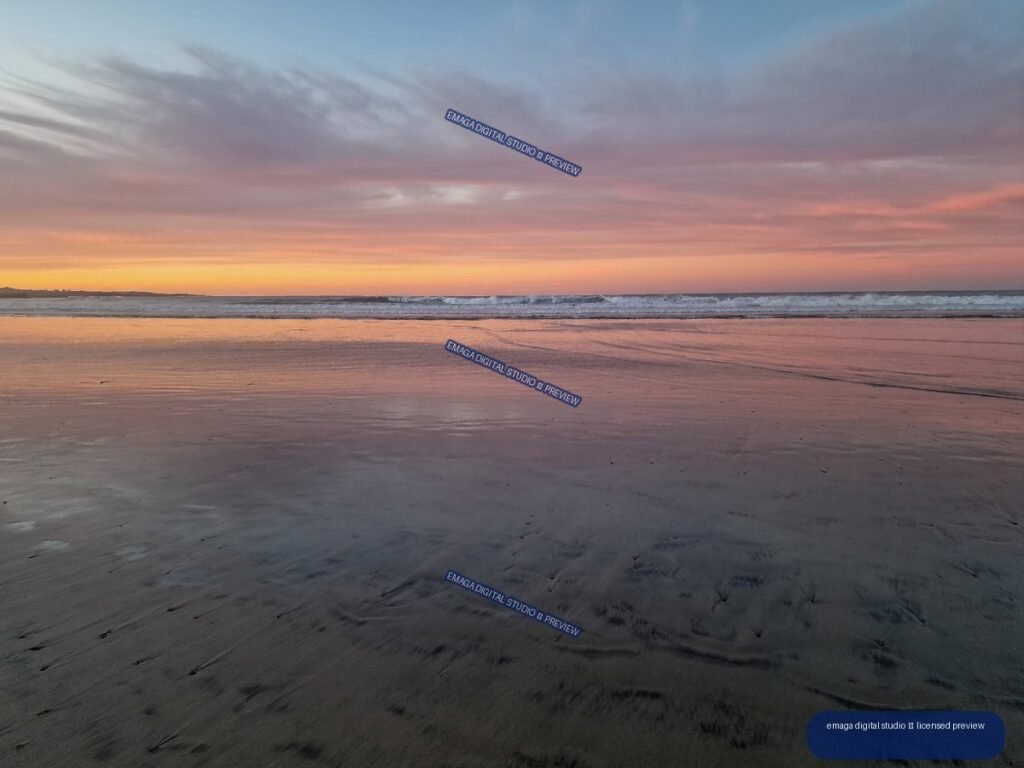Pastel sunset over ocean waves at Famara Beach, reflected across broad wet sand.