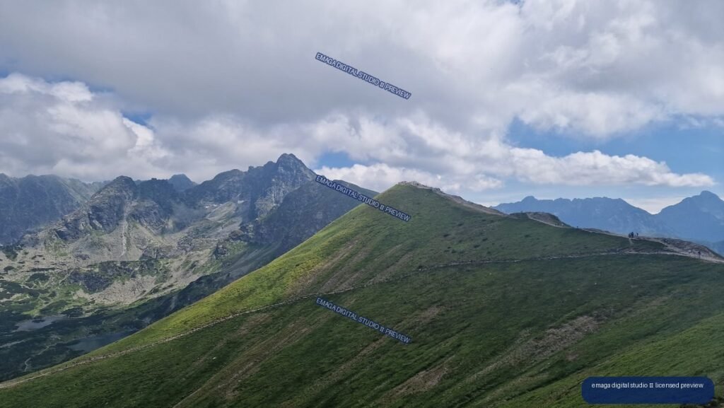 Green alpine ridge with a narrow trail, jagged gray peaks, distant mountains, and dramatic clouds.