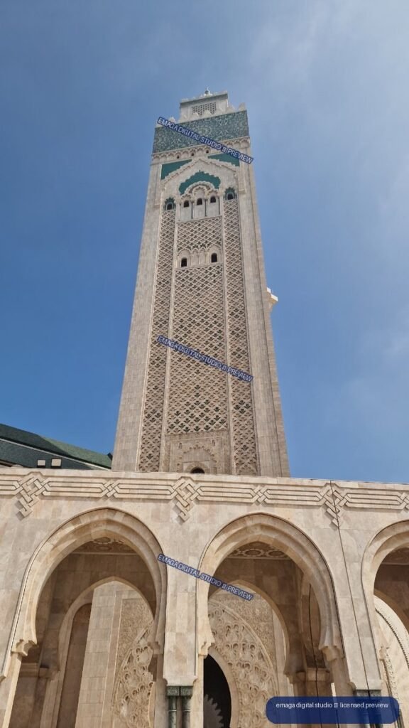 Ornate mosque minaret and arched facade beneath blue sky — Casablanca, Morocco