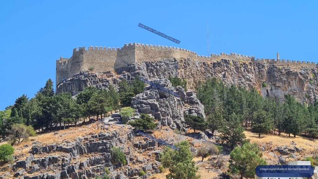 Fortified stone walls above rocky hillside in Lindos, Rhodes, Greece