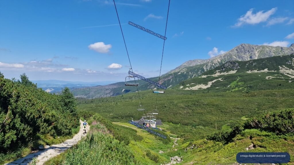 Mountain trail leading toward a chairlift beneath rugged gray peaks in the Tatra Mountains.
