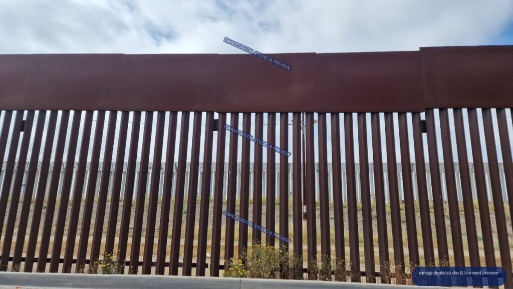 Vertical Steel Barrier Under a Cloudy Blue Sky — Tijuana, Mexico