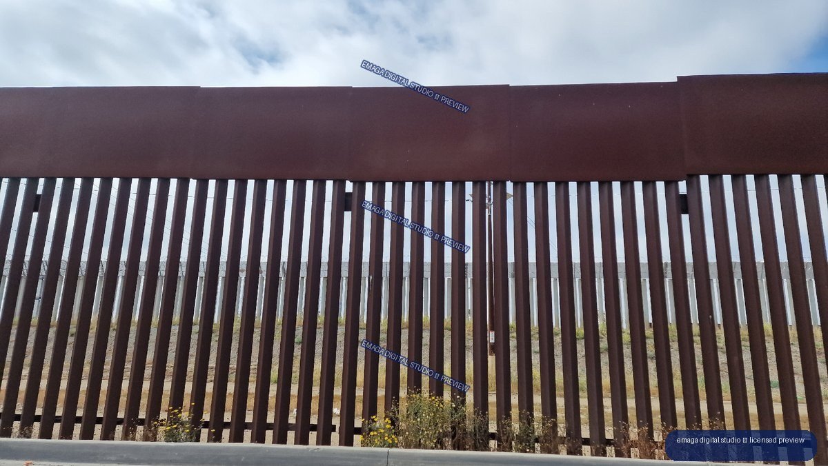 Vertical Steel Barrier Under a Cloudy Blue Sky — Tijuana, Mexico