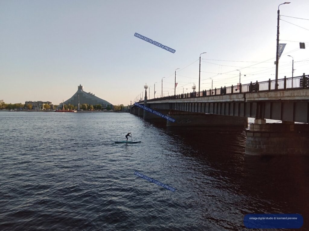 Riga, Latvia Riverside Bridge and Paddleboarder at Sunset