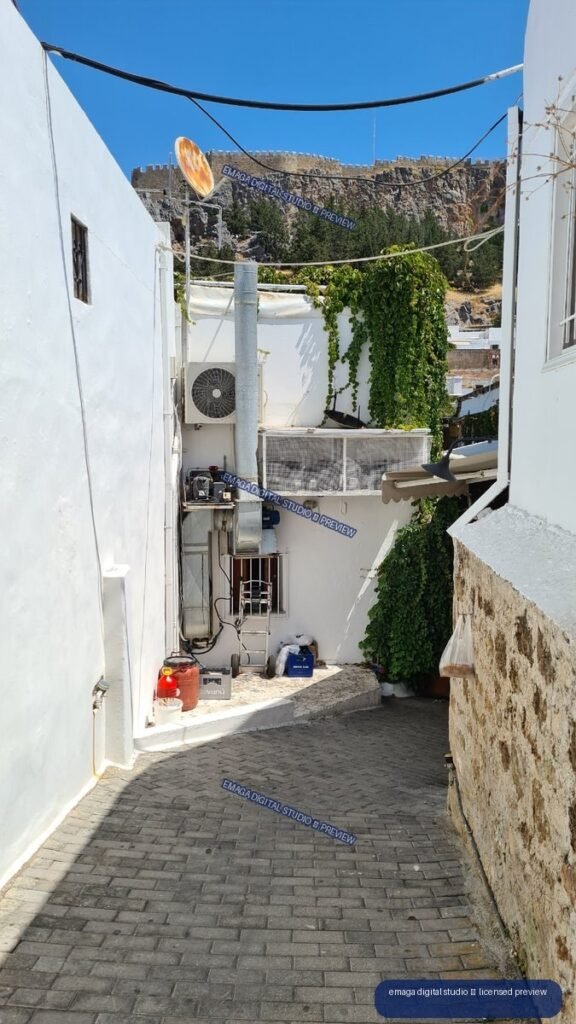 Narrow Whitewashed Alley with Stone Fortification in Lindos, Rhodes, Greece