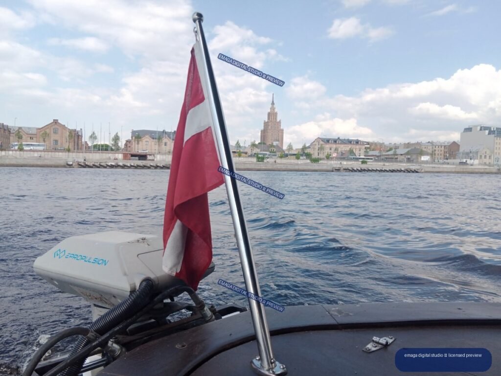 Latvian flag and waterfront cityscape viewed from a boat in Riga, Latvia