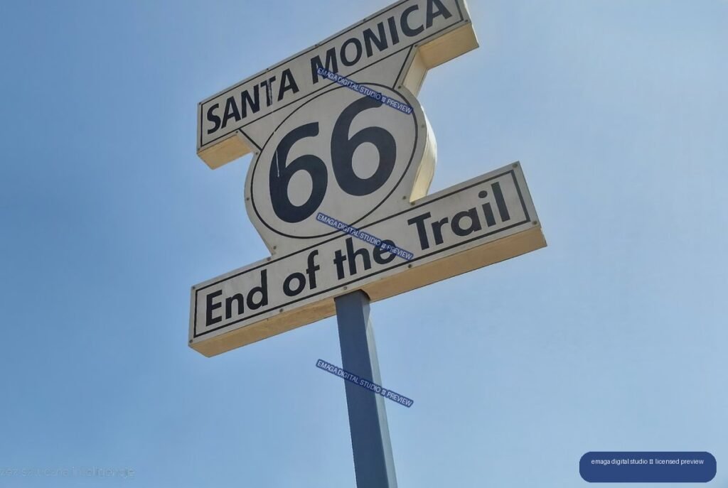 Low-angle view of a Santa Monica Route 66 End of the Trail sign against a clear blue sky.