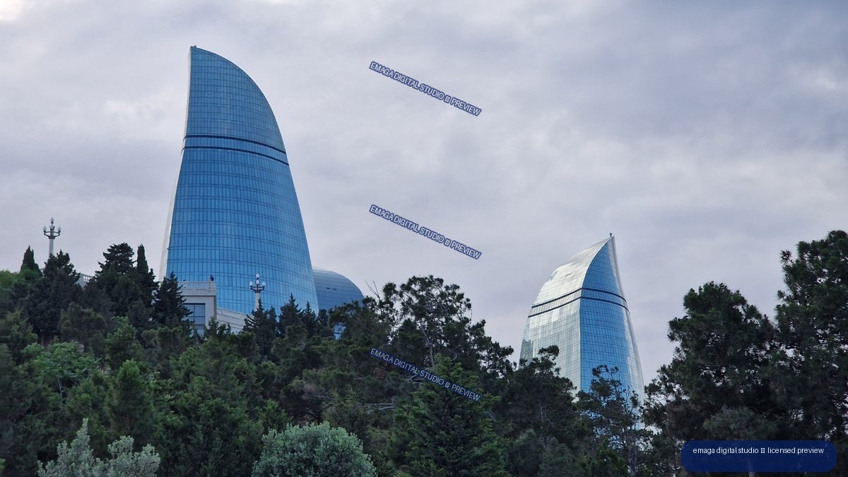 Curved glass towers above trees in Baku, Azerbaijan